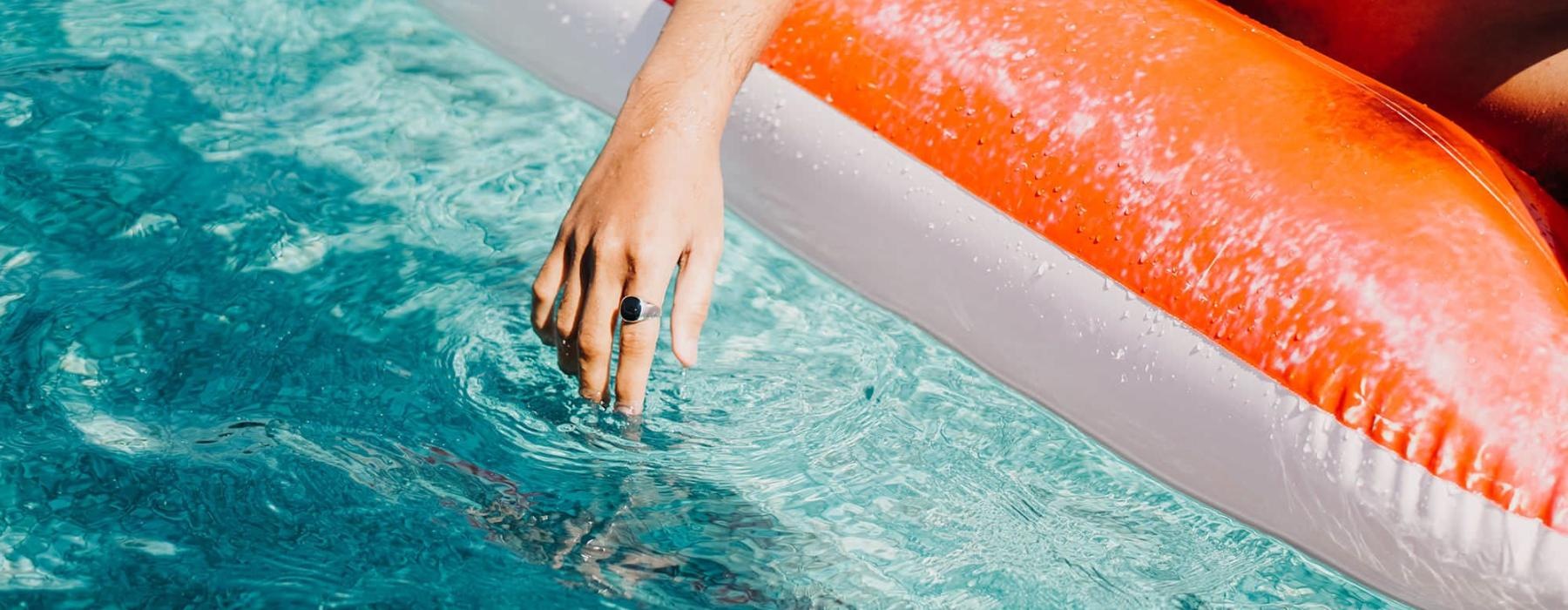 woman dangles her hand in the pool as she floats in an inflatable vessel