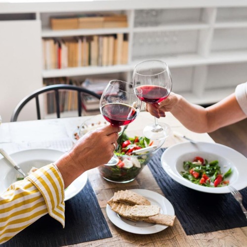 a couple sits at a table eating with wine